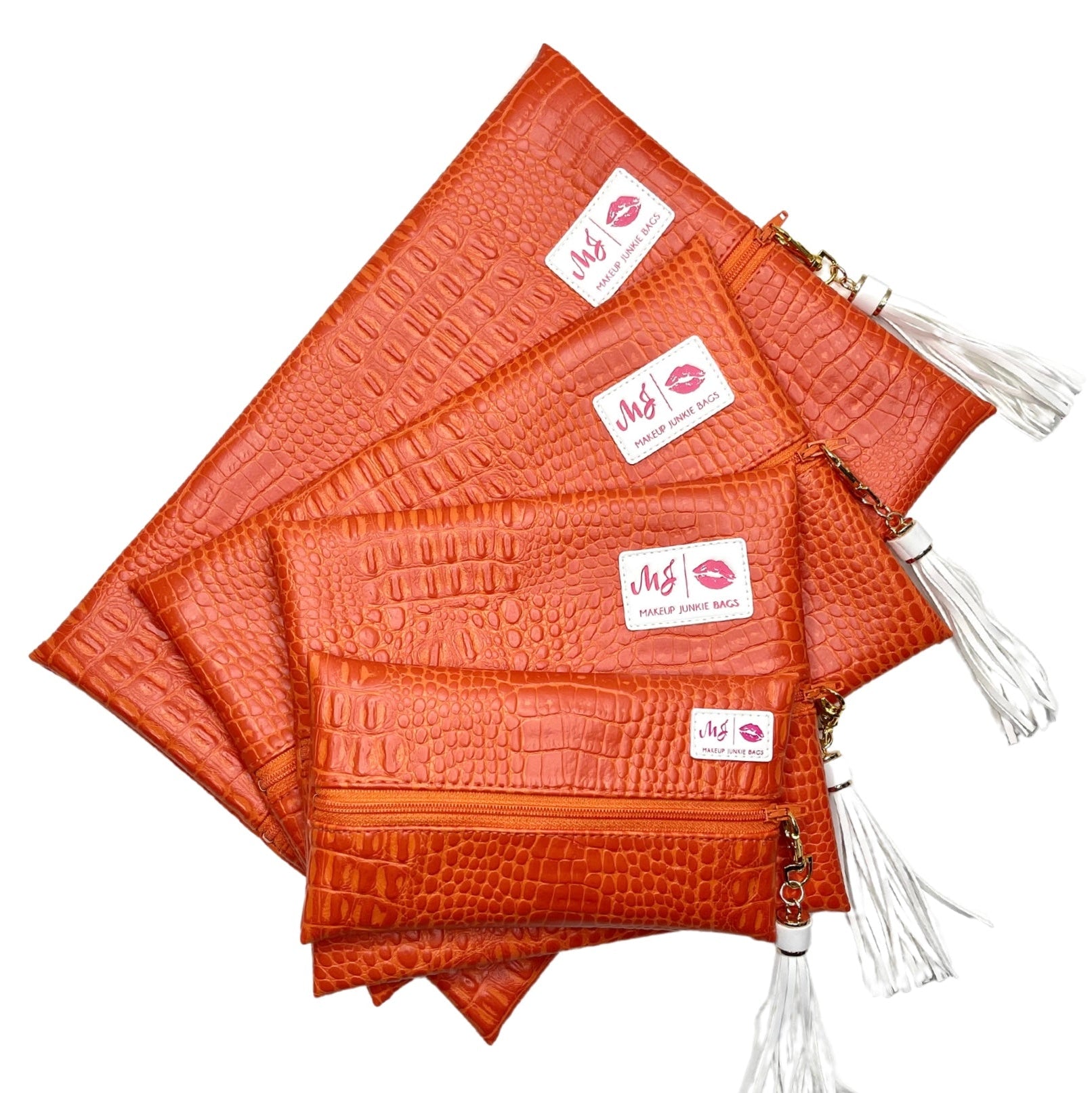 Set of orange crocodile-textured pouches with white tassels on a white background