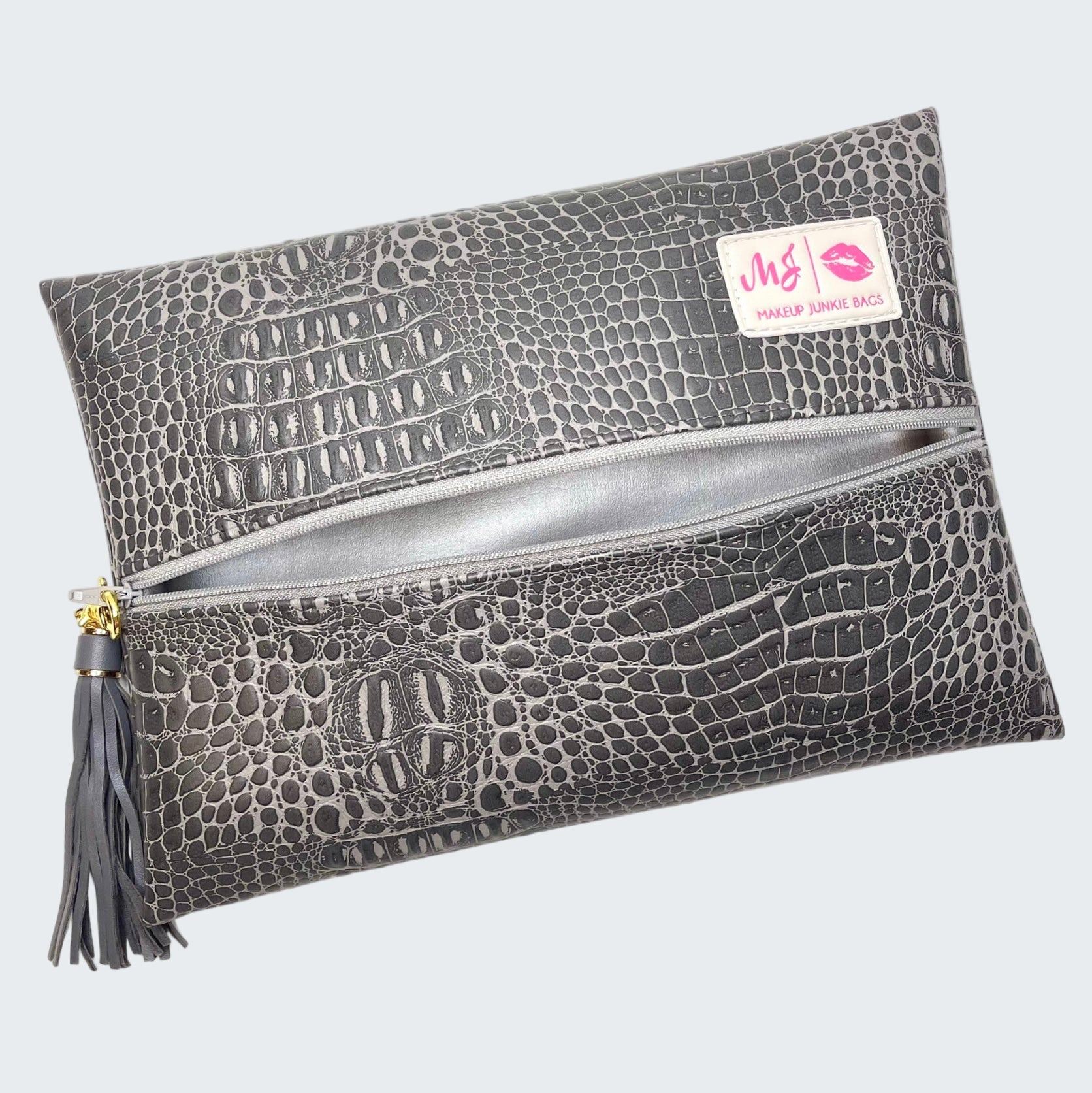 Gray crocodile-patterned makeup bag with a visible brand label on a white background