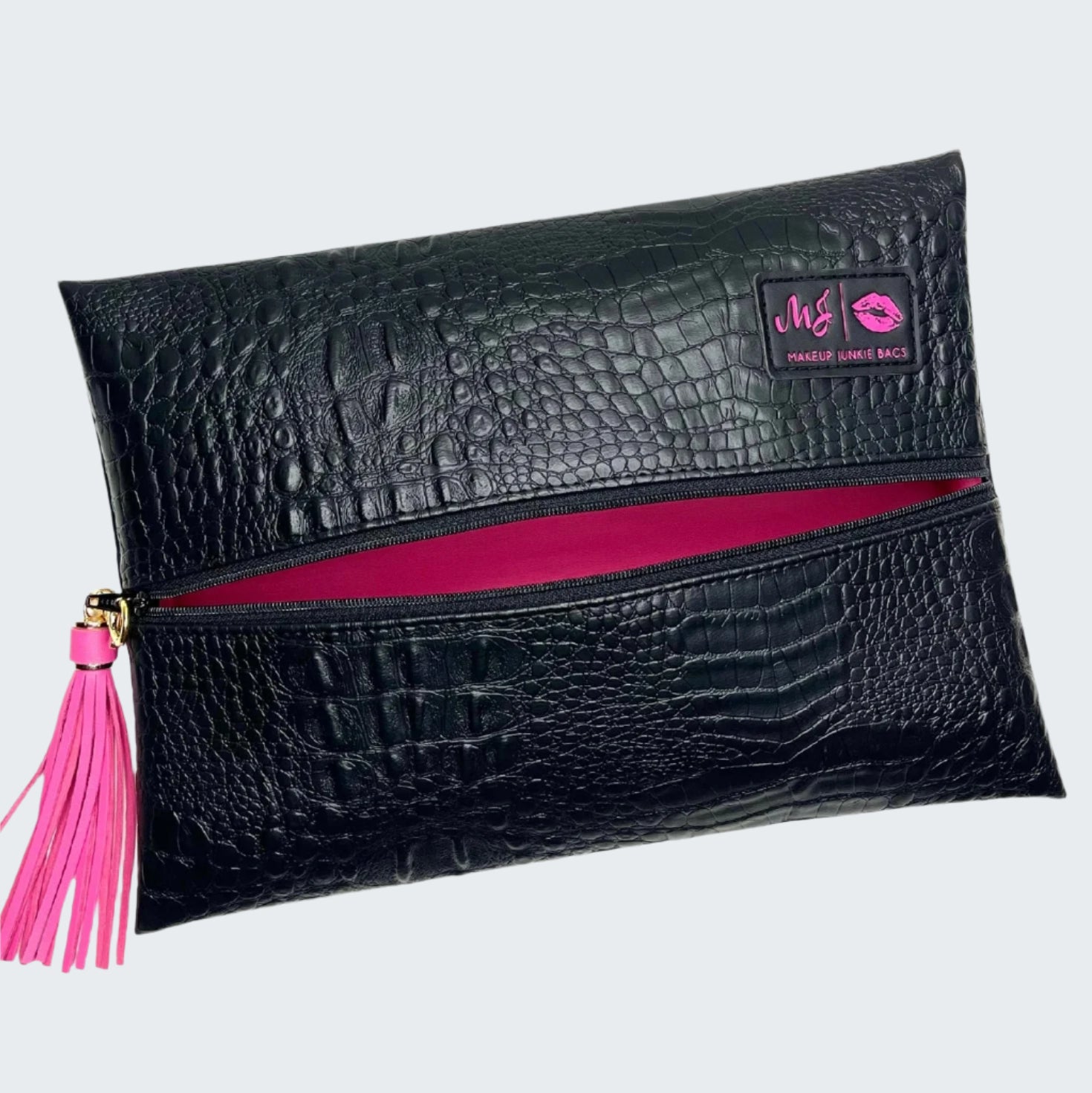 Black crocodile-patterned clutch bag with pink zipper and tassel on a white background