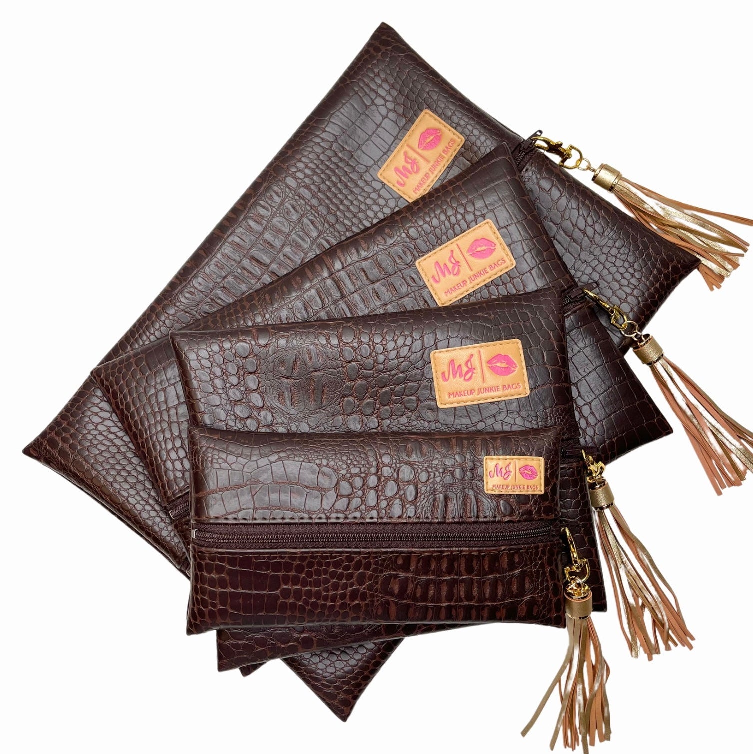 Set of brown leather pouches with gold tassels and visible brand label on a white background