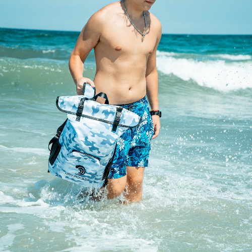 Man in blue swim trunks holding a surfboard in the ocean
