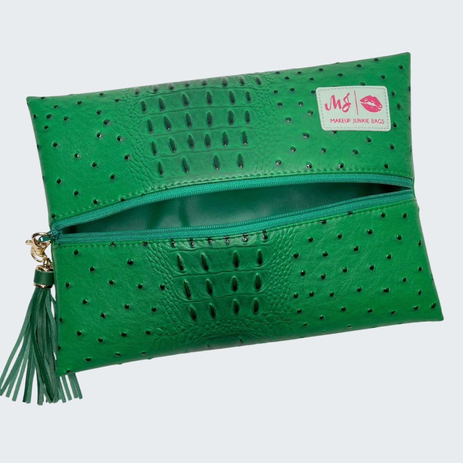 Green clutch bag with perforated design and tassel on a white background