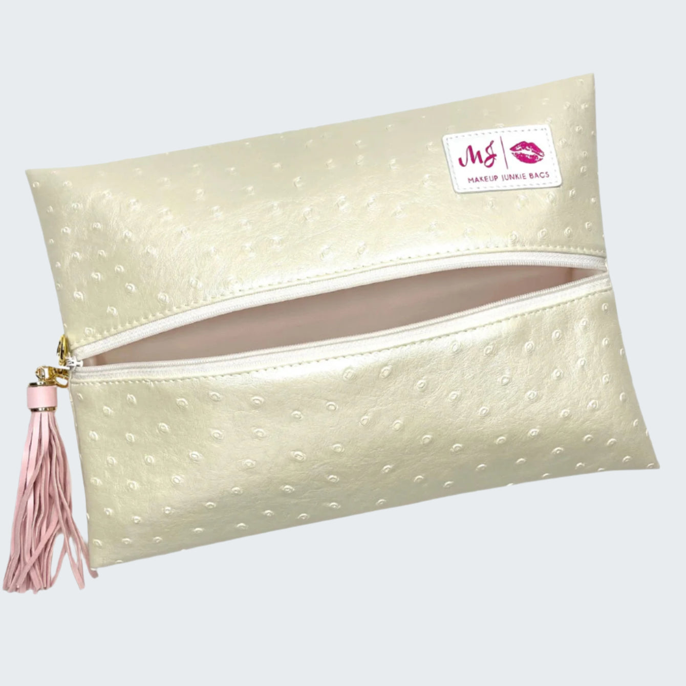 Makeup bag with polka dot pattern and pink tassel on a white background