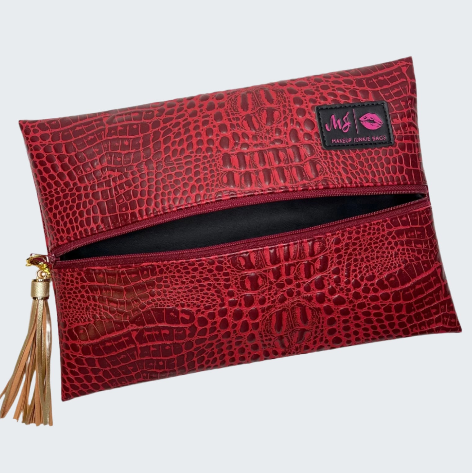 Red crocodile-patterned makeup bag with a tassel on a white background