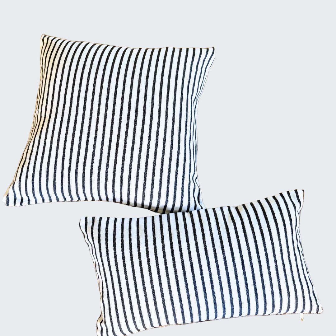 Two black and white striped pillows on a woven mat.