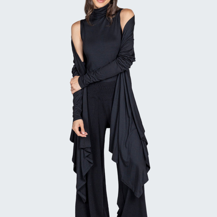 Woman wearing a black outfit with ruffled details on a gray background