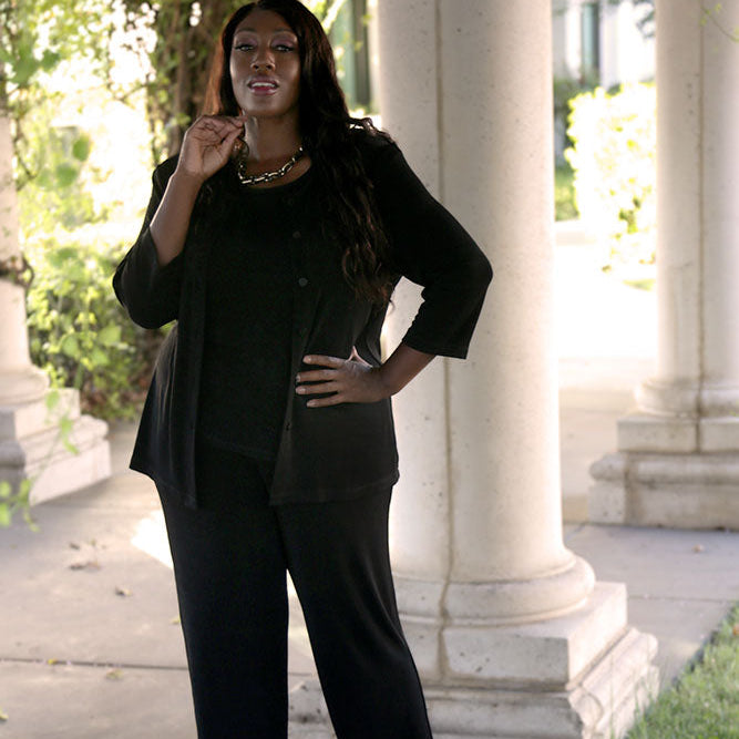 Woman in black outfit standing outdoors near classical architecture