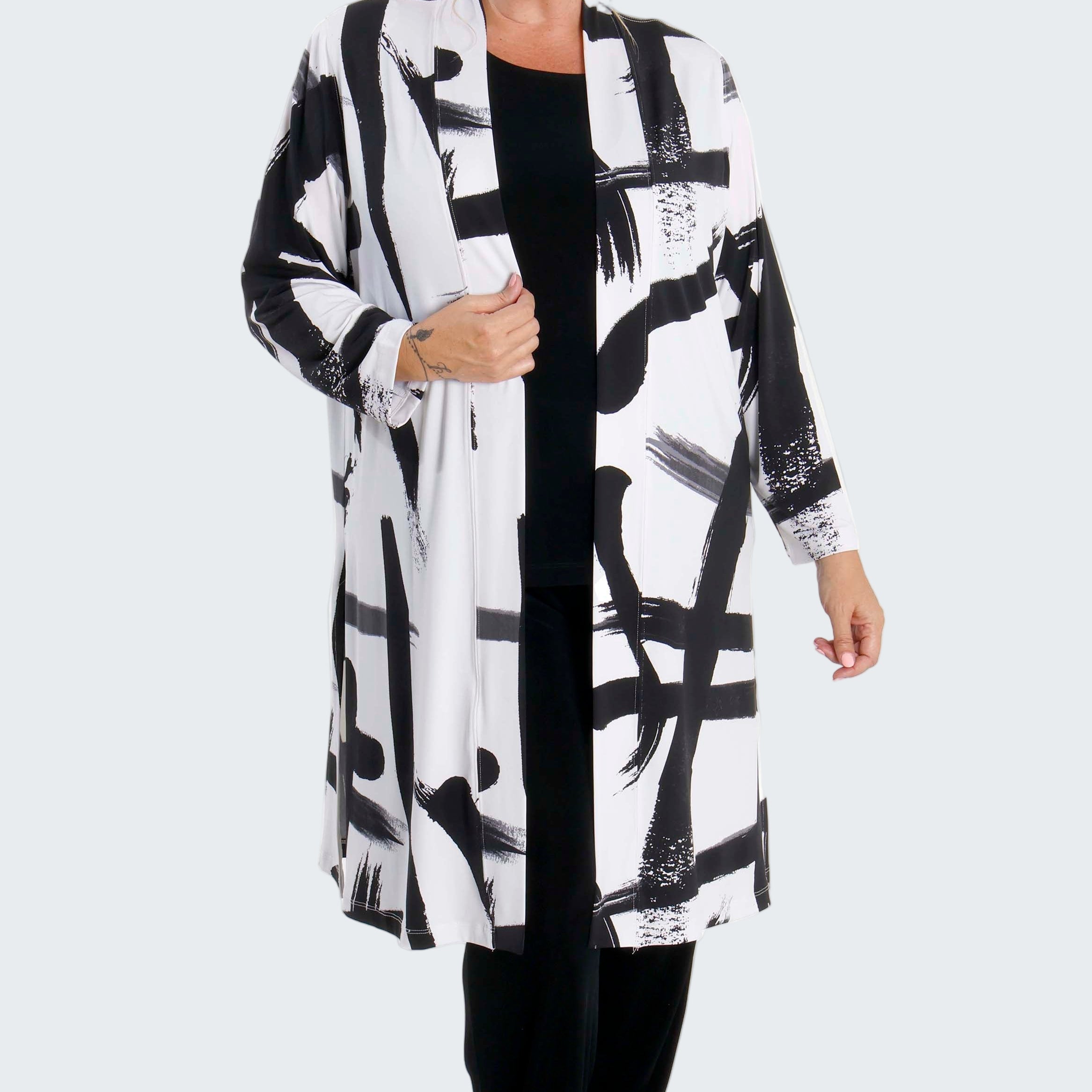 Woman wearing a black and white abstract patterned coat on a white background