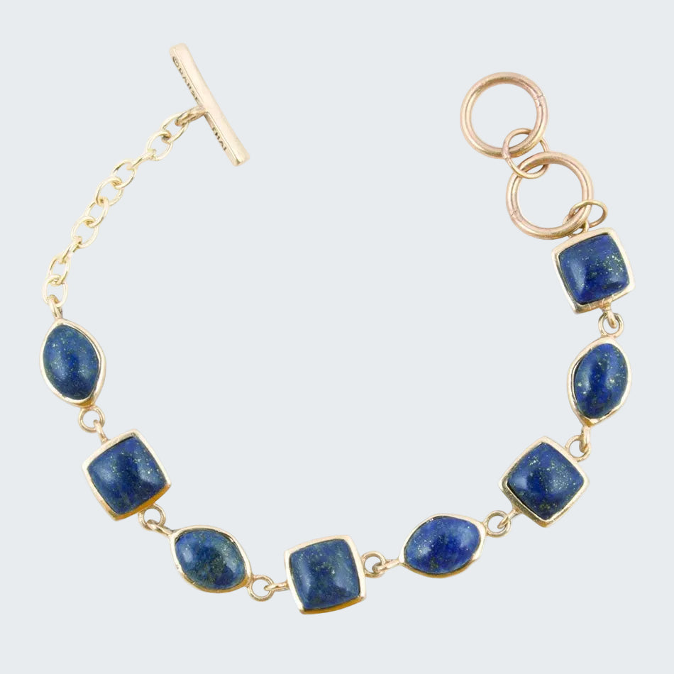 Gold bracelet with blue stones on a white background