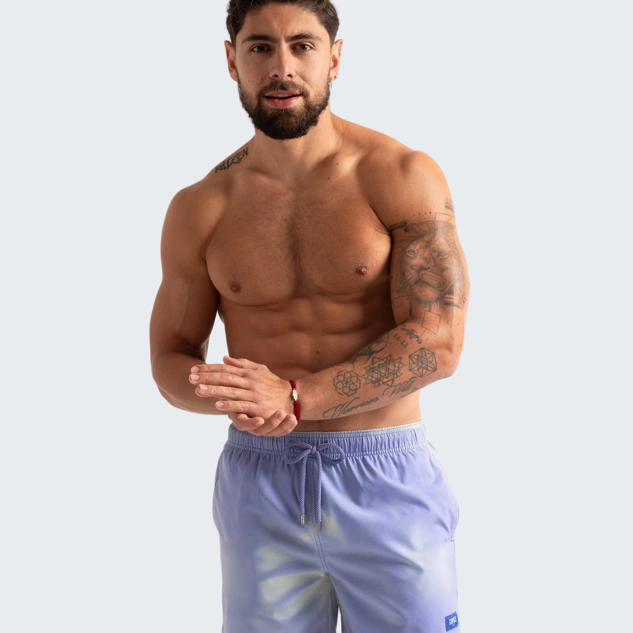 Man wearing light blue swim shorts on a plain background
