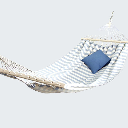 Hammock with a blue pillow on a stone patio by a poolside