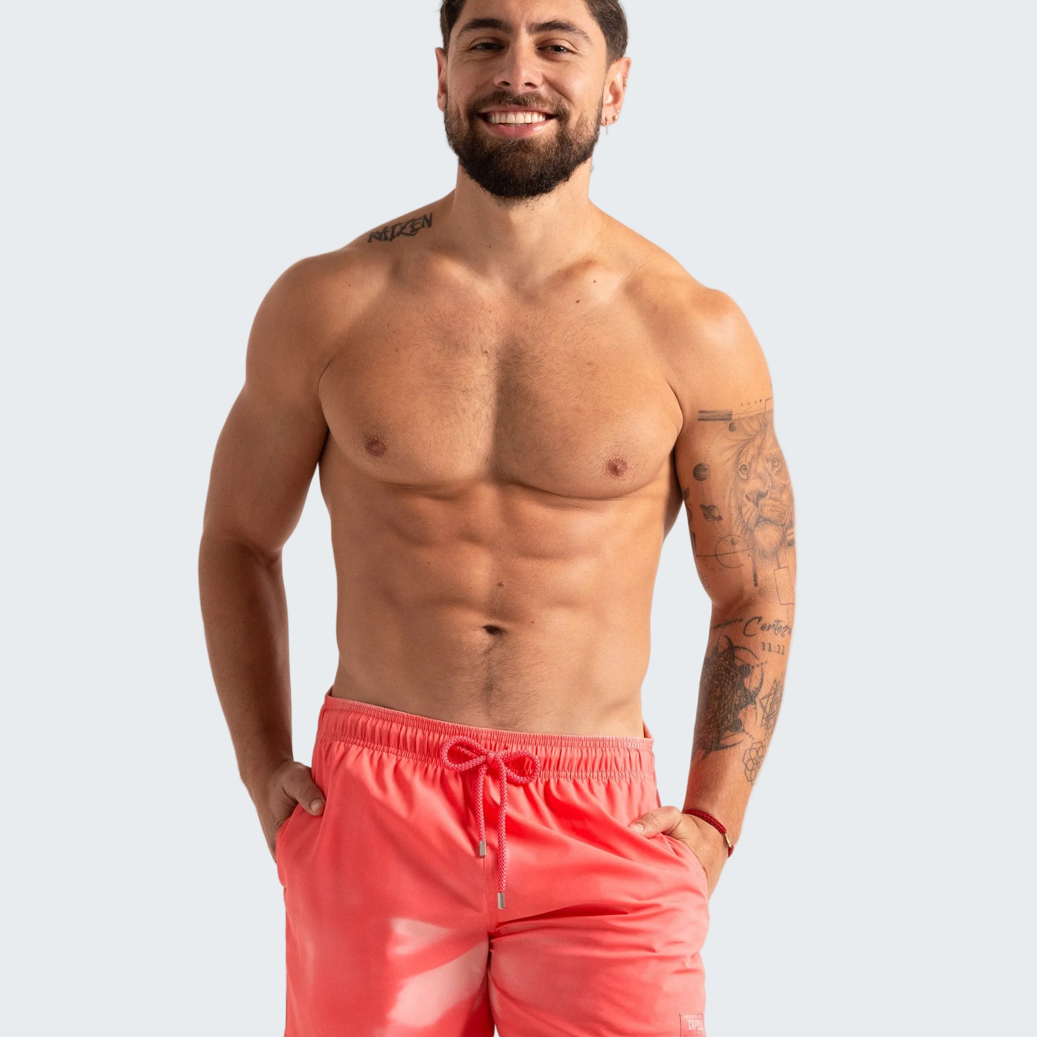 Man wearing pink swim shorts against a plain background