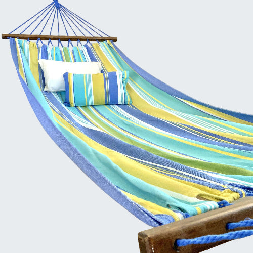 Colorful striped hammock with pillows on a wooden stand in a room.