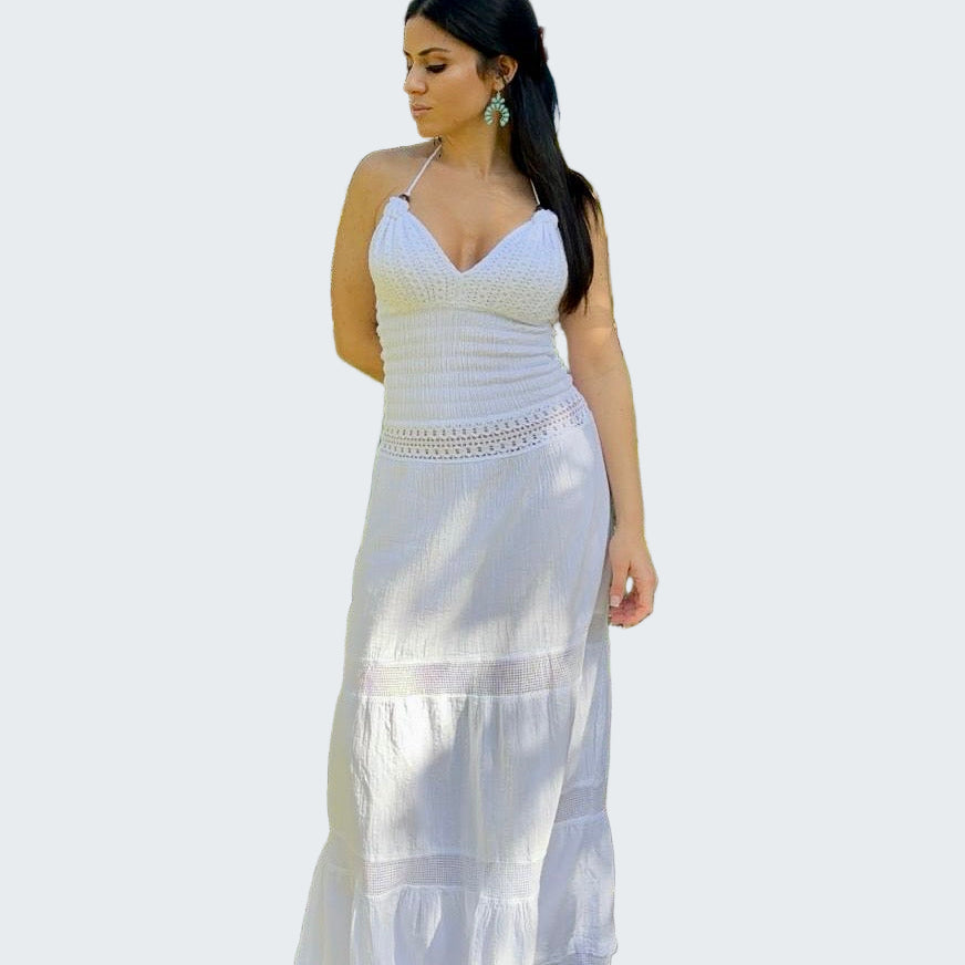 Woman in a white dress standing outdoors near trees and grass