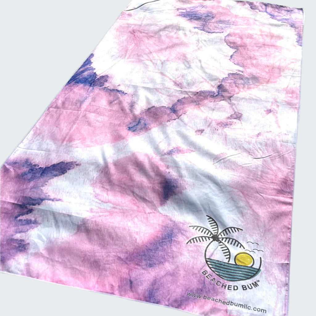 Pink and purple tie-dye towel with a palm tree design on sand