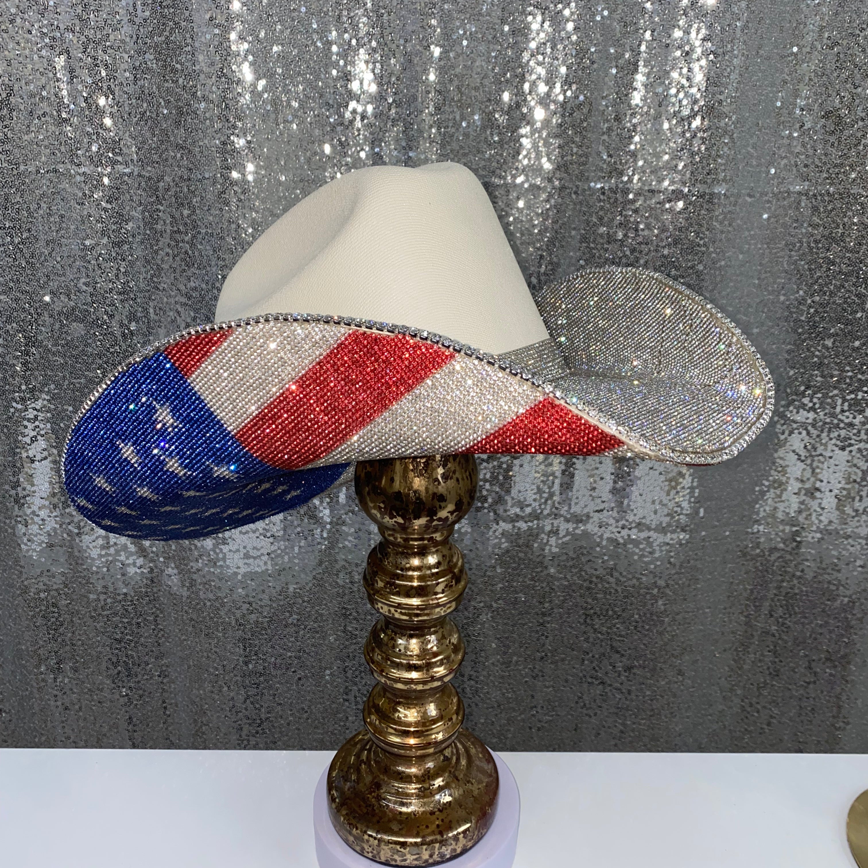 Decorative lamp with a beaded American flag design on a metallic stand against a textured gray background.
