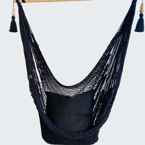 Navy blue hammock chair with a pillow in a room with decorative elements.