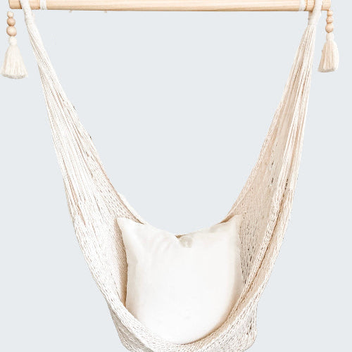 White hammock chair with a pillow in a room with decorative elements.