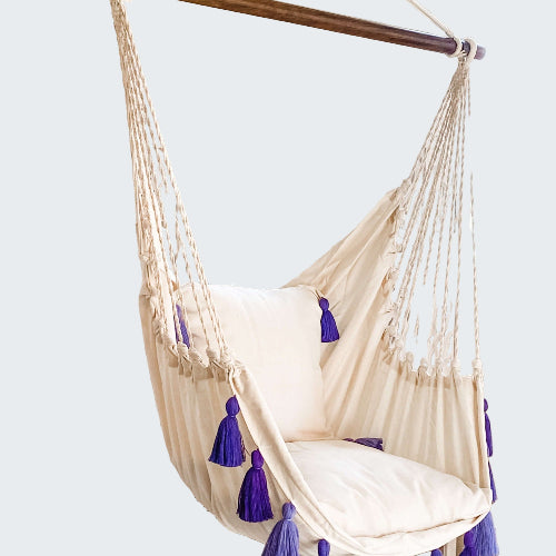 White hanging chair with purple tassels in a room with decorative elements.