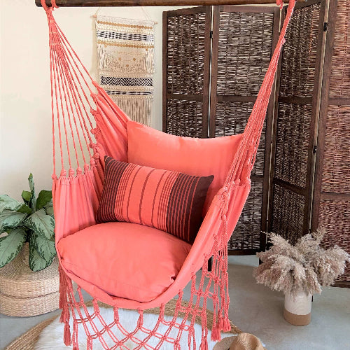 Coral hammock chair with decorative pillows in a room setting.