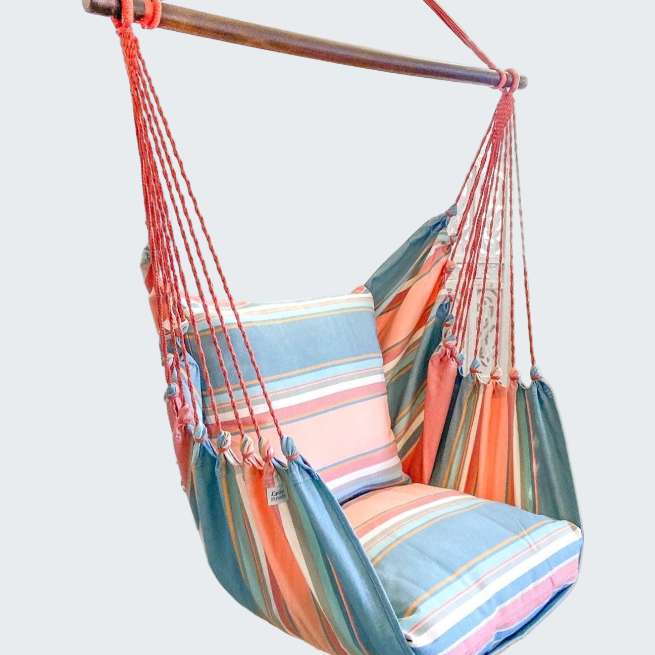 Colorful striped hammock chair hanging indoors with a decorative plant and rug.