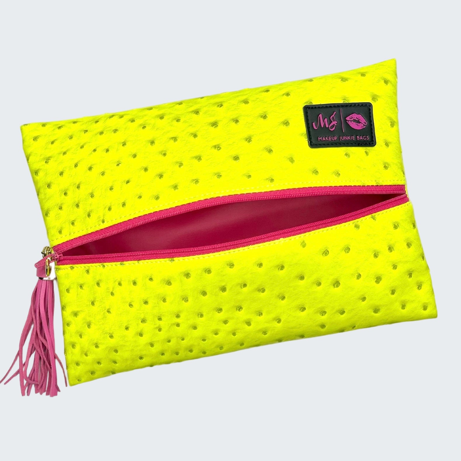 Yellow clutch bag with pink zipper and tassel on a white background