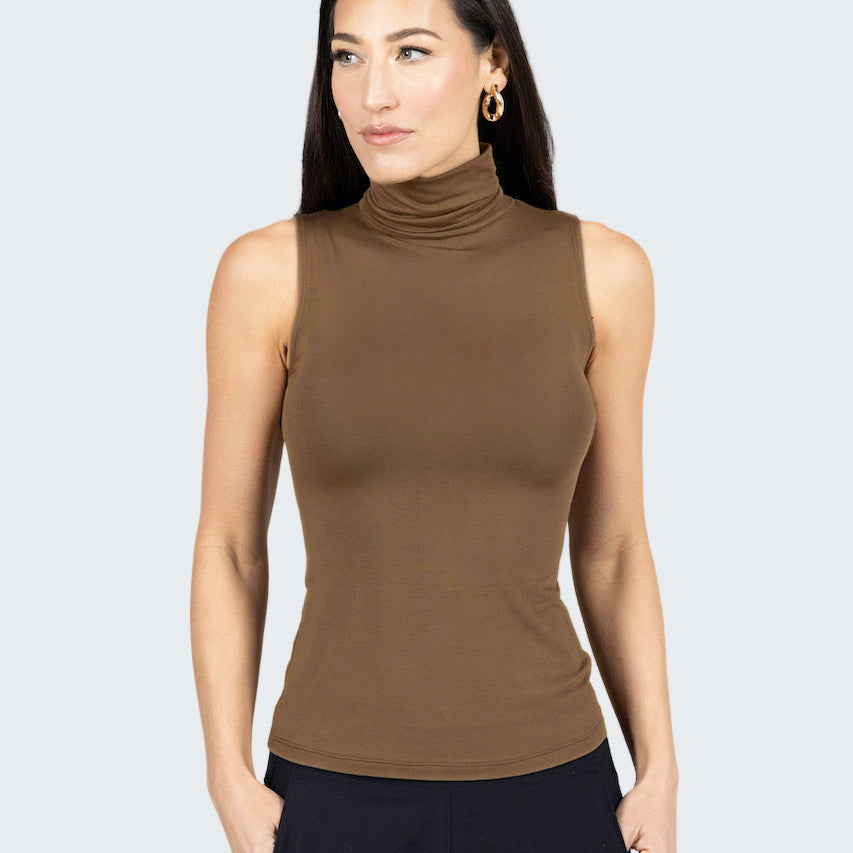 Woman wearing a brown sleeveless turtleneck top against a gray background
