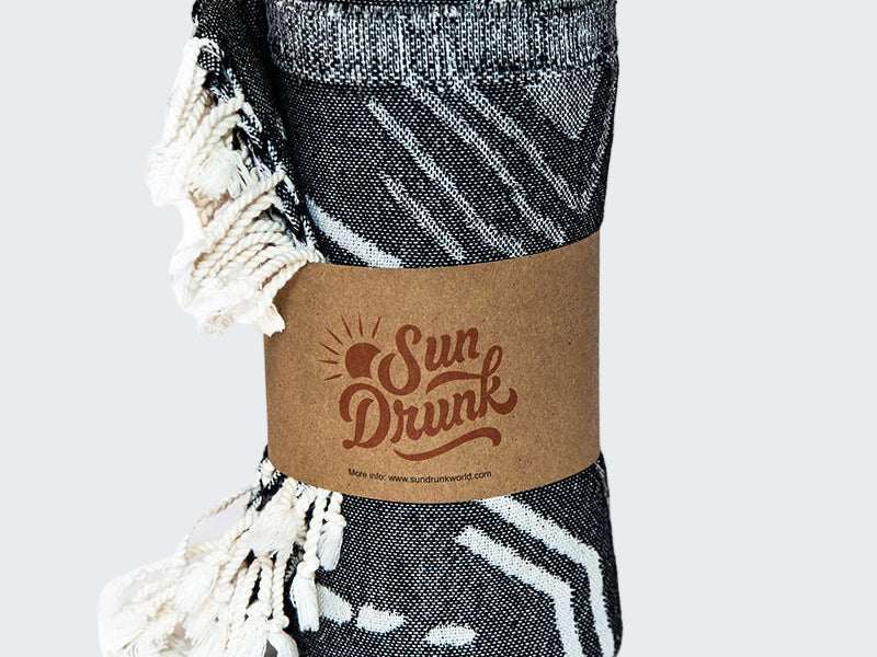Folded black and white patterned blanket with a 'Sun Drunk' label on a white background