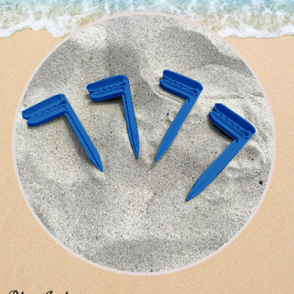 Four blue sand anchors on a sandy surface with ocean waves in the background.