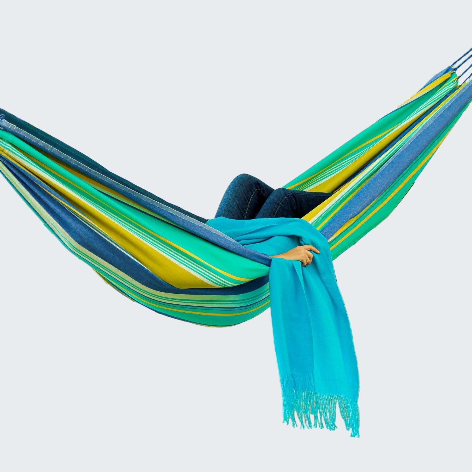 Person relaxing in a colorful striped hammock with a scenic background