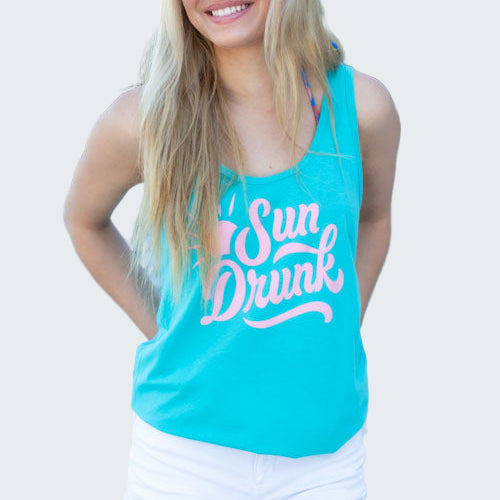 Woman wearing a turquoise tank top with 'Sun Drunk' text by a pool.