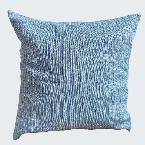 Blue textured pillow on a wooden stool against a light background