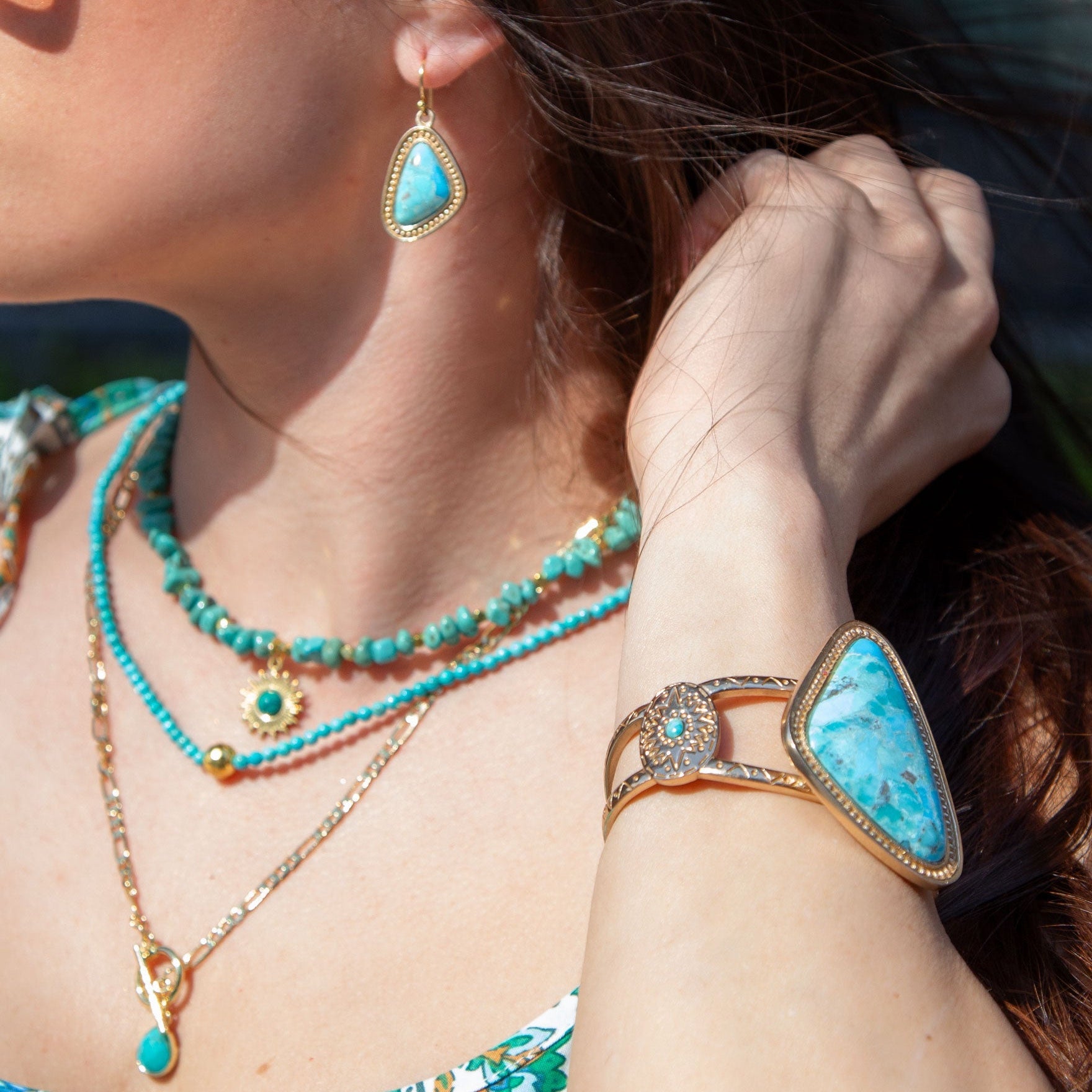 Close-up of a person wearing turquoise jewelry including earrings, necklace, and bracelet.
