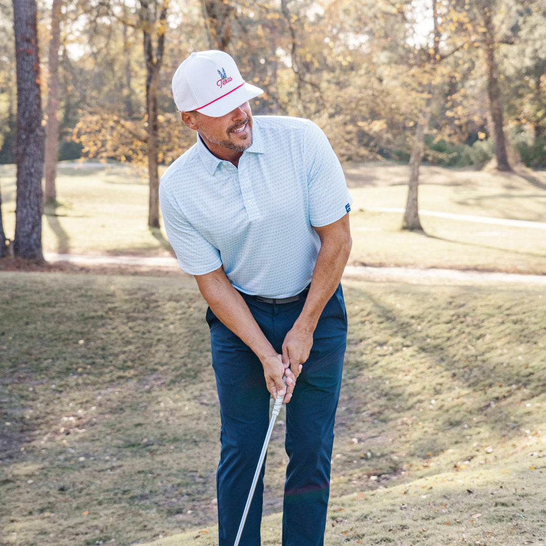 Man playing golf on a grassy course with trees in the background