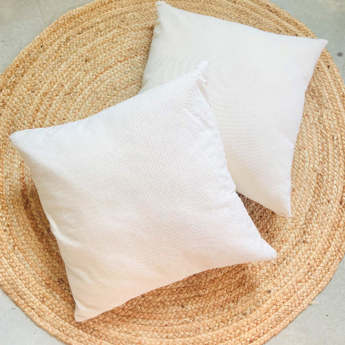 Two white pillows on a woven mat