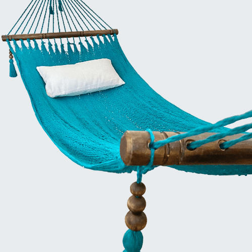 Turquoise hammock with wooden posts and tassels in a room setting.