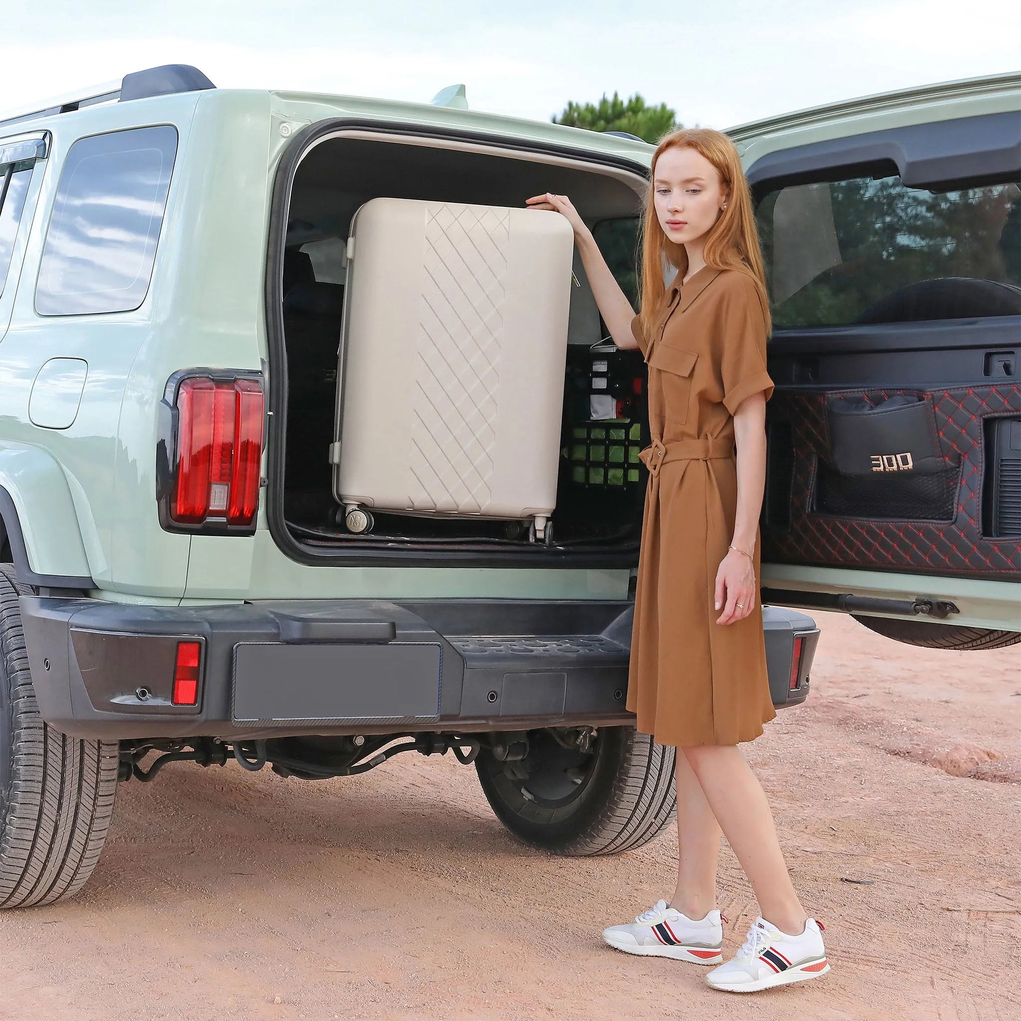 Woman in a brown dress loading a suitcase into the trunk of a light green SUV.