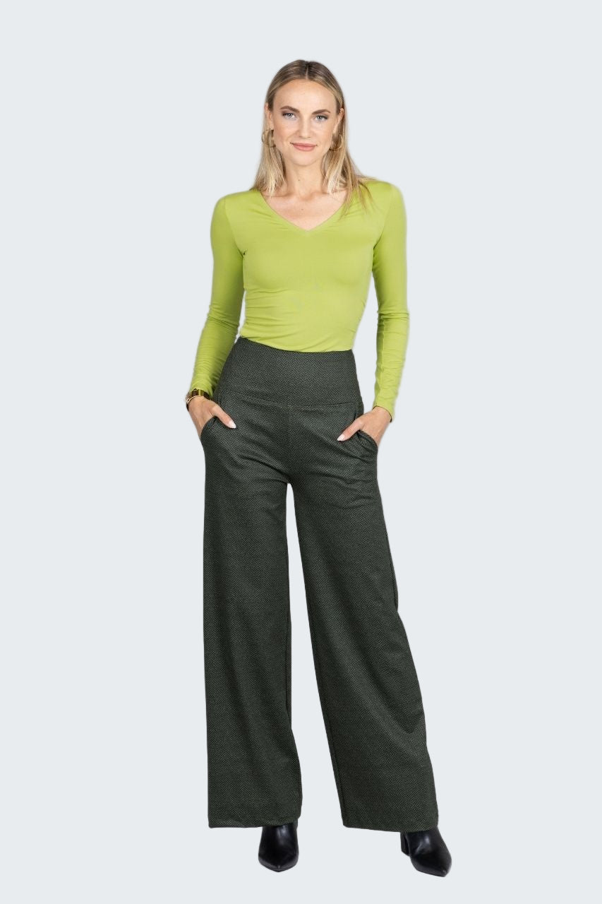Woman wearing a green top and dark green wide-leg pants on a white background