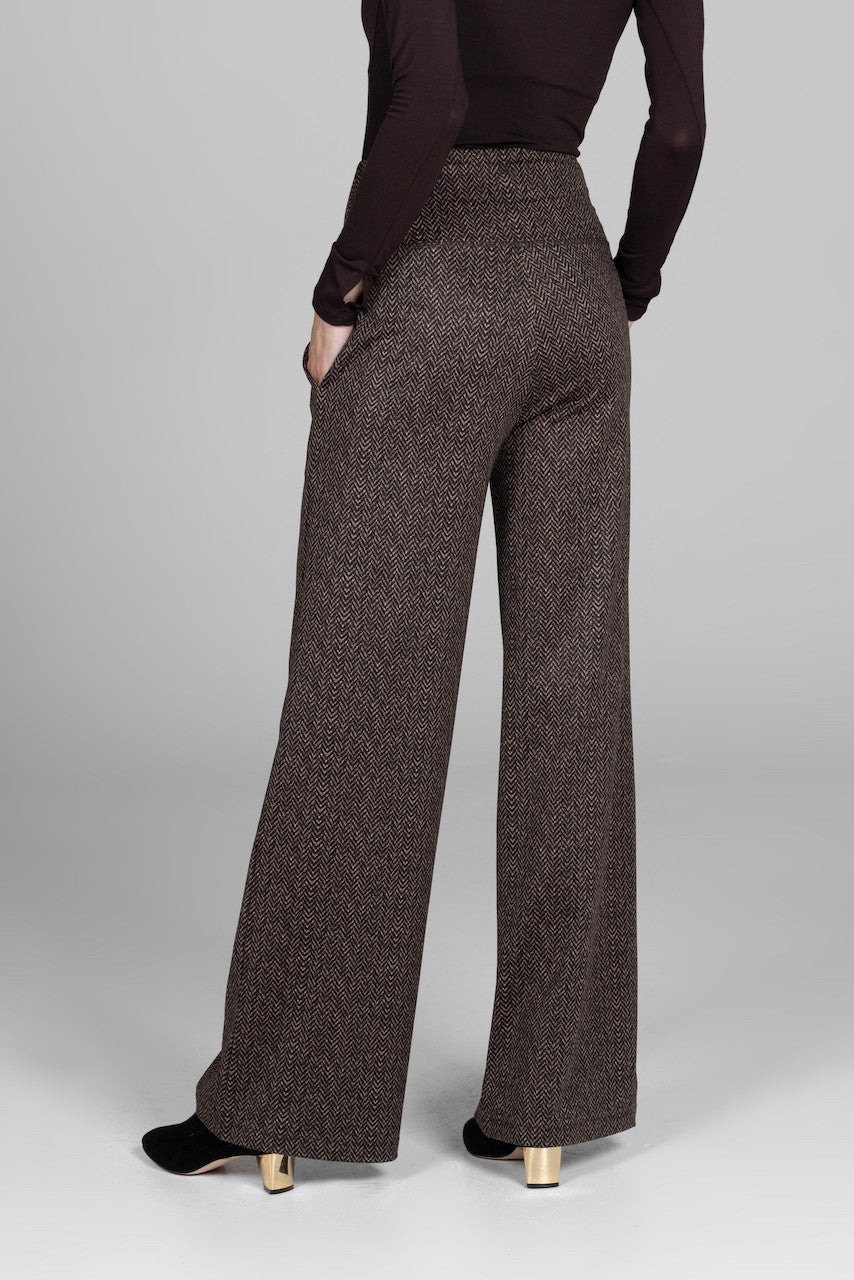 Brown herringbone pants worn by a person on a gray background
