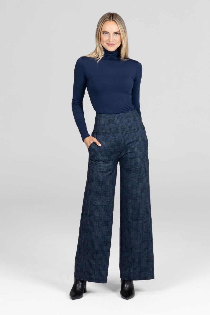 Woman wearing a navy turtleneck and plaid pants on a white background