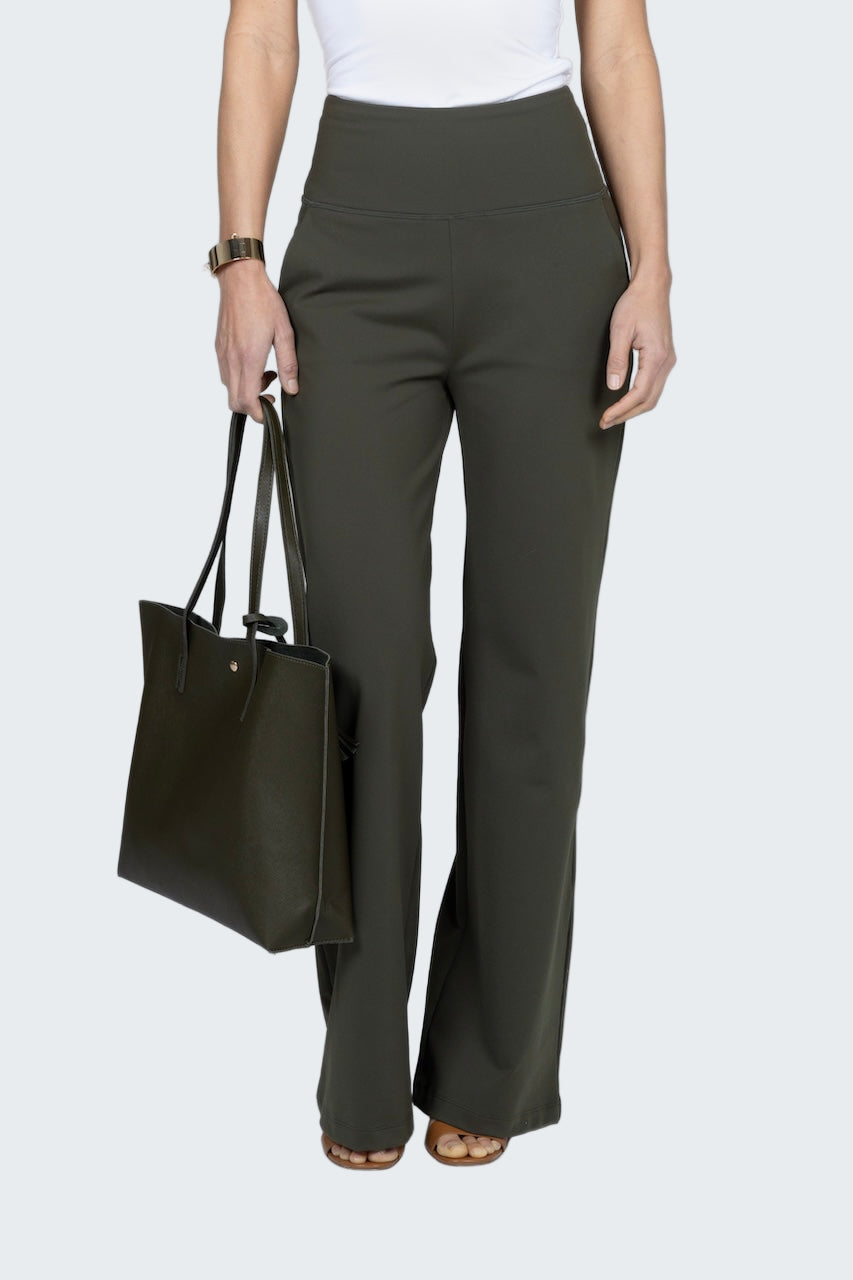 Person wearing olive green pants holding a black tote bag on a white background