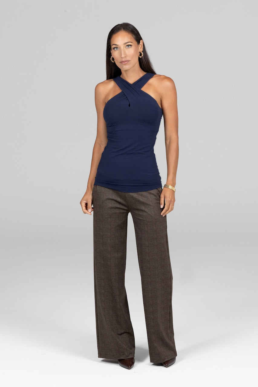 Woman wearing a navy halter top and brown pants on a gray background