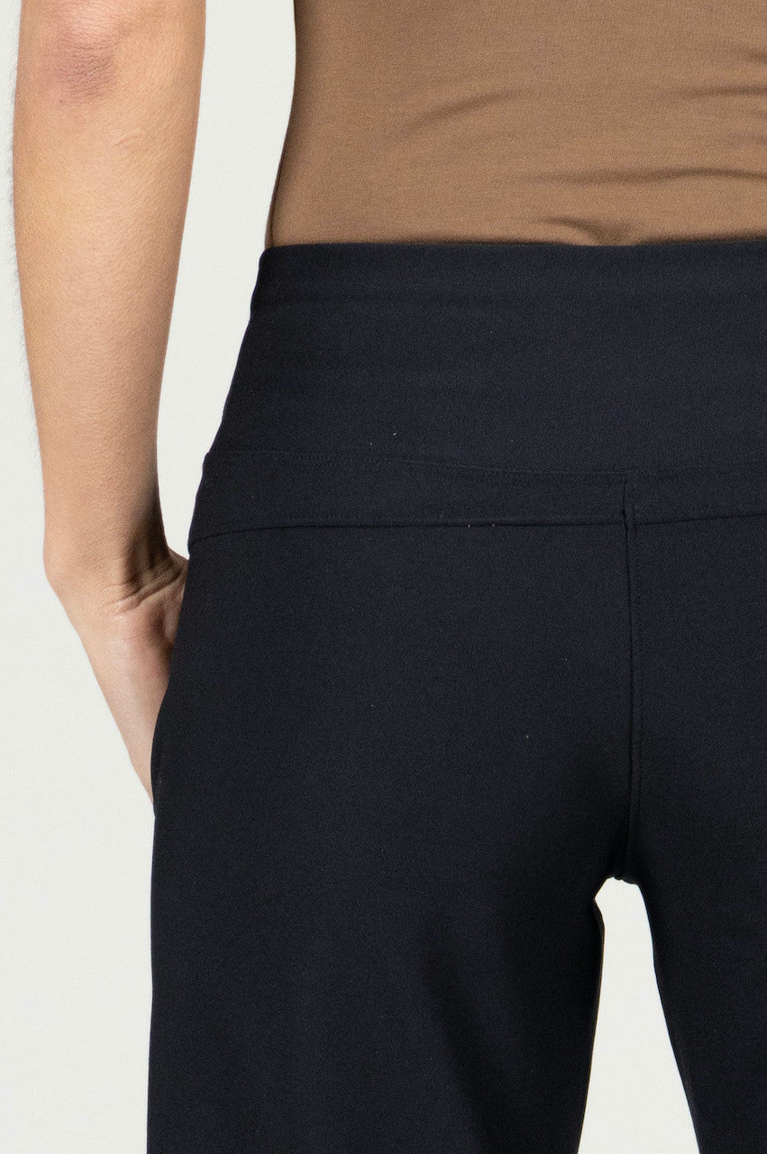Person wearing black pants with a plain background