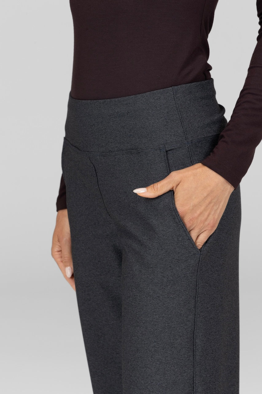 Person wearing dark gray pants with a plain background