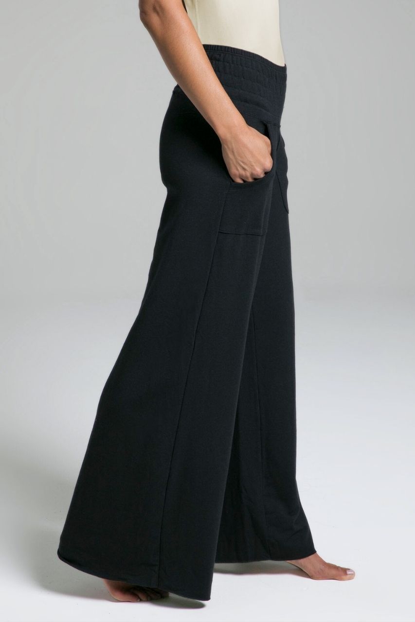 Person wearing black wide-leg pants on a plain background