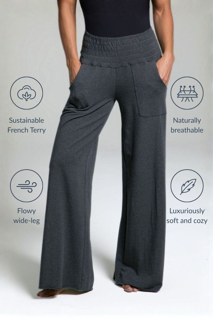 Dark gray wide-leg pants worn by a person on a light gray background with sustainability benefits listed.