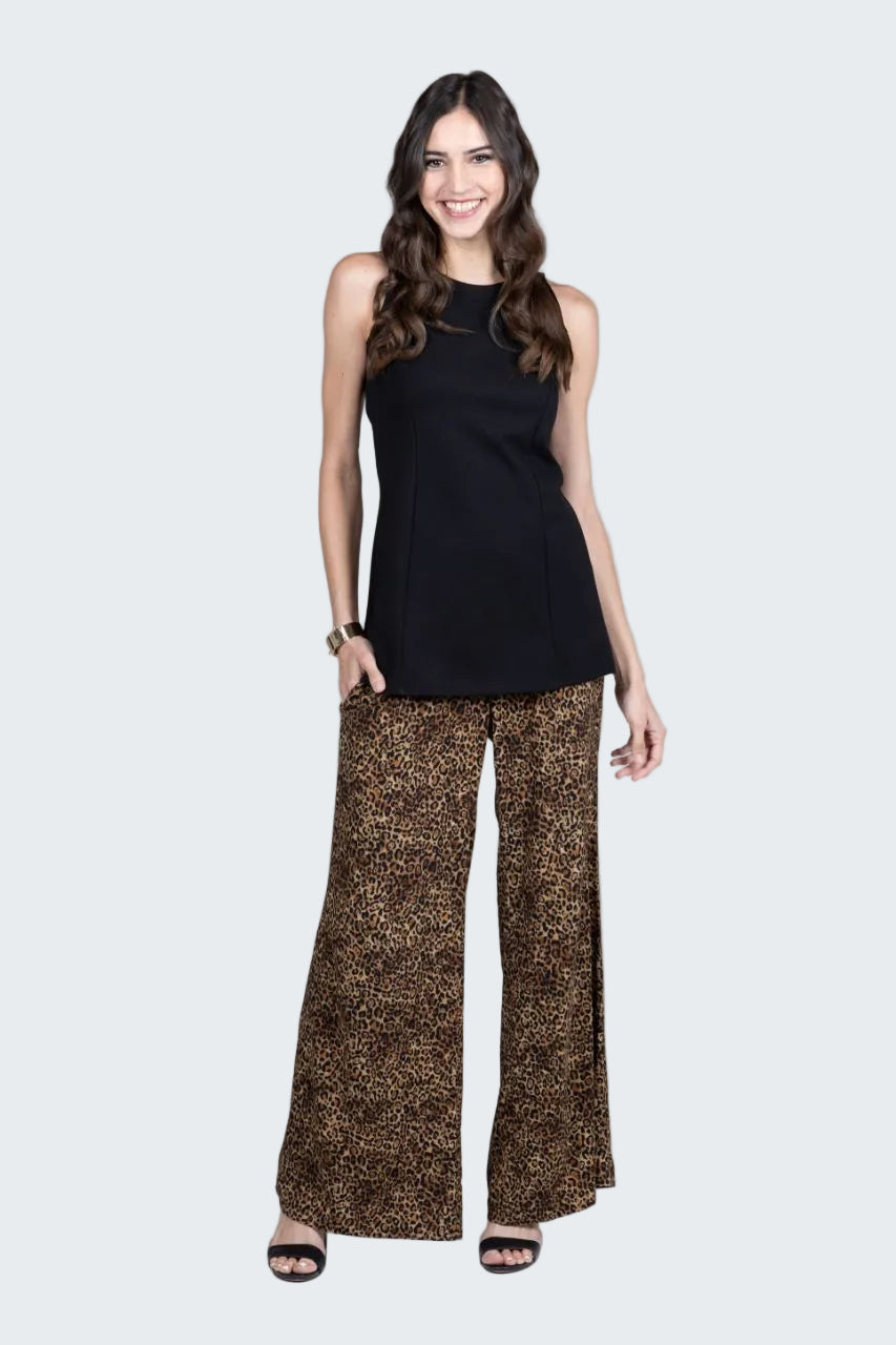 Woman wearing a black sleeveless top and patterned pants on a white background