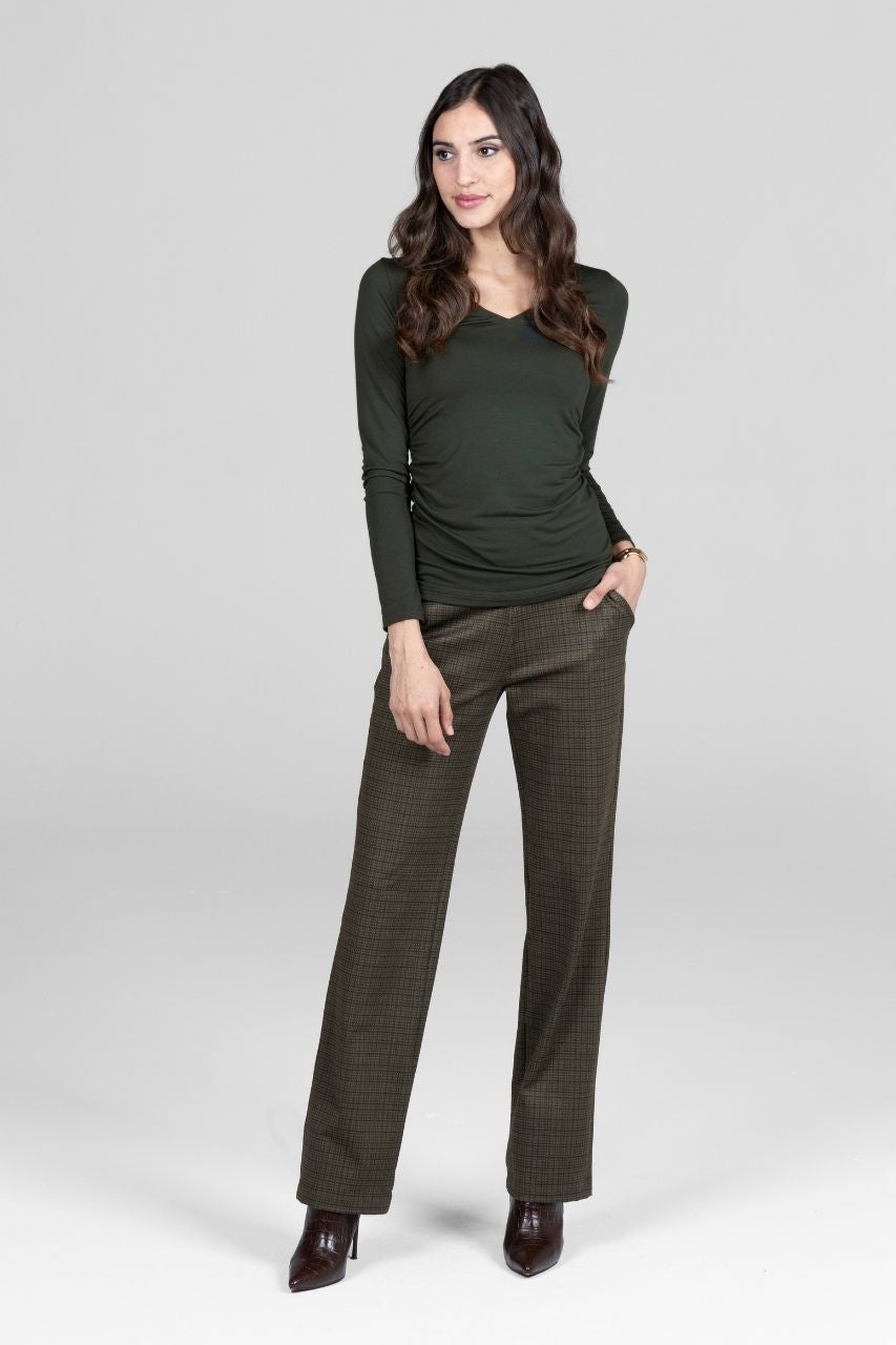 Woman wearing a green long-sleeve top and matching pants on a white background