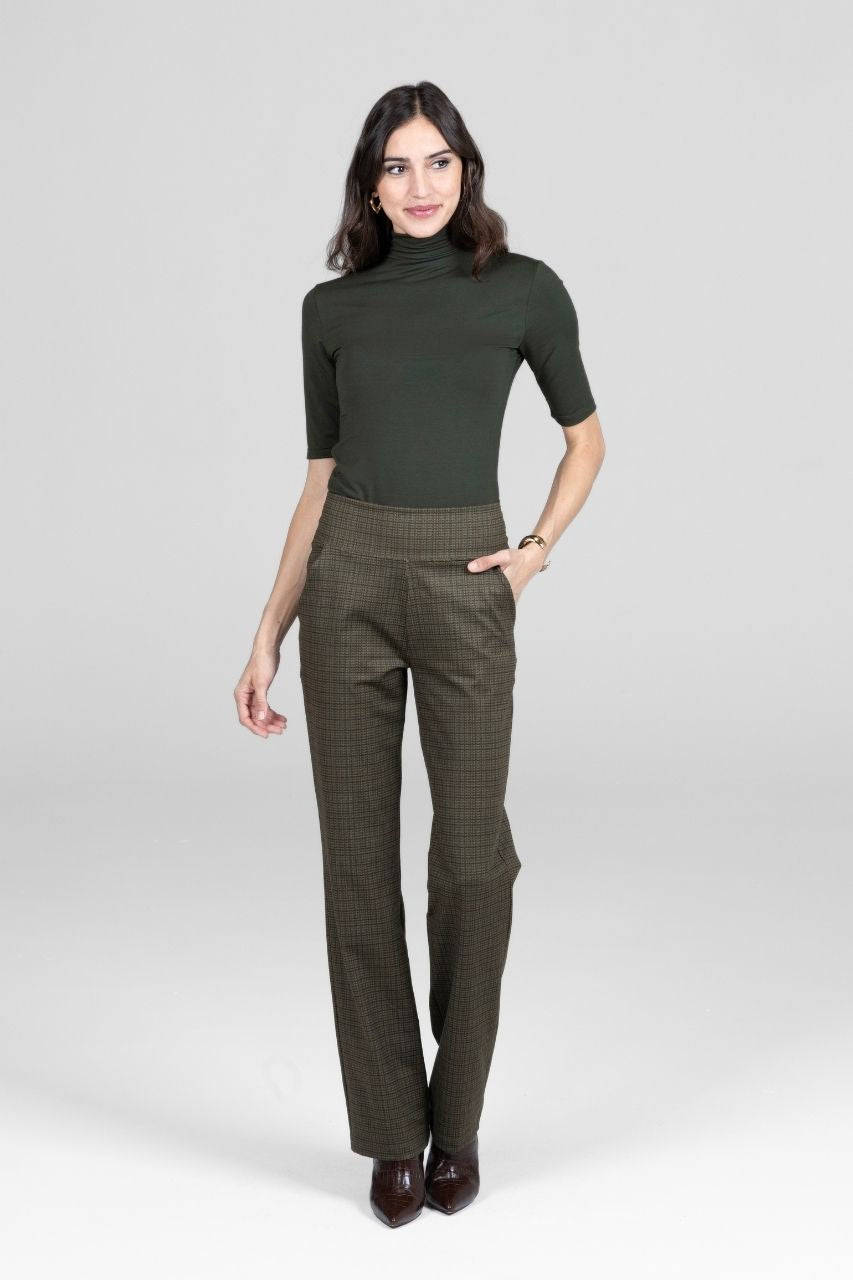 Woman wearing a green turtleneck and dark green pants on a white background