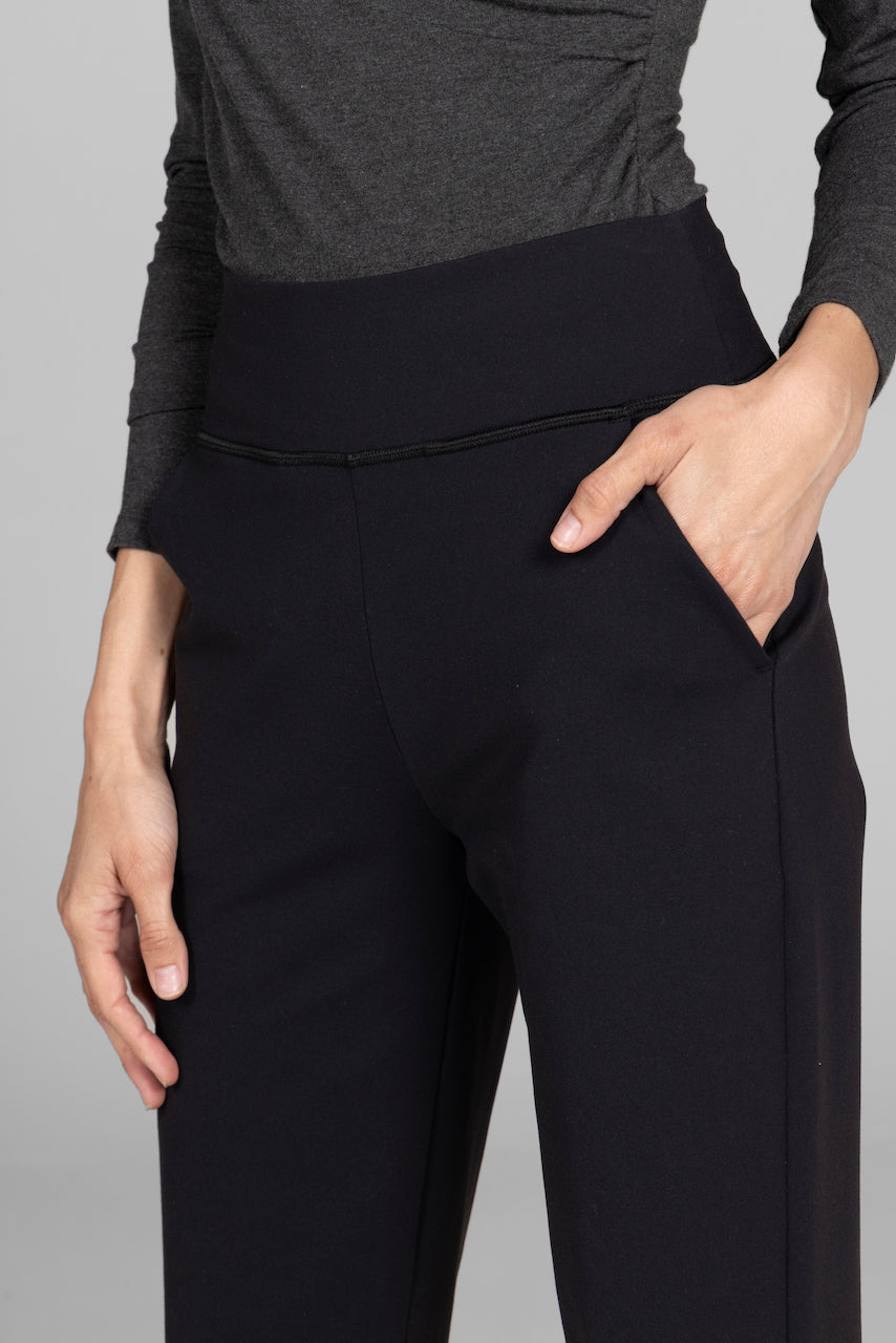 Person wearing black pants with a gray top on a gray background